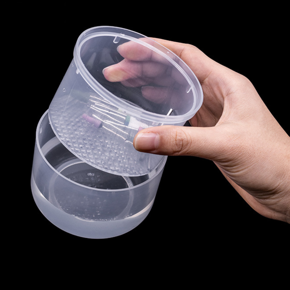 Hand holding a clear plastic container with a lid on a black background