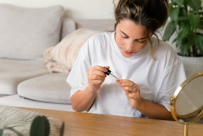Woman doing her nails at home in a cozy living room with a natural beginner manicure setup and soft daylight.