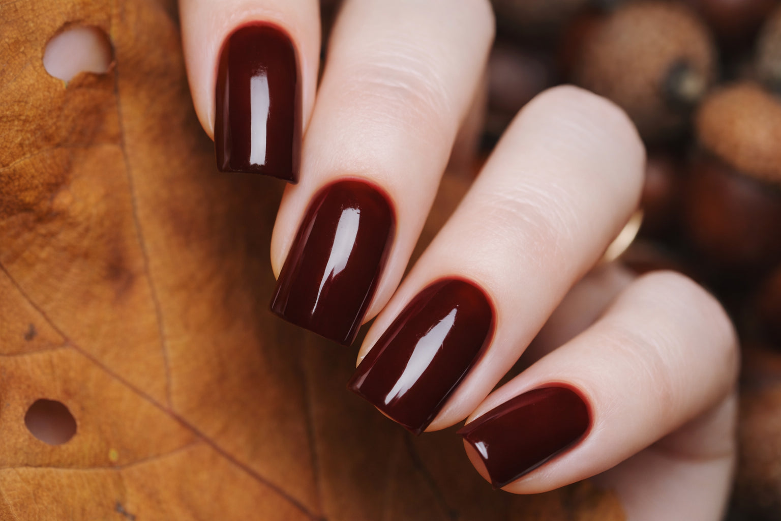 Close-up of deep red glossy manicure on square-shaped nails with a clean, polished finish