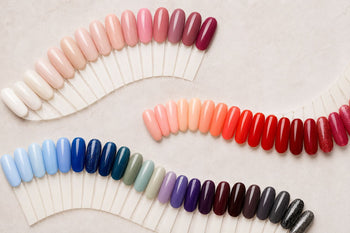 Curved rows of colorful nail swatches on a light neutral background, featuring soft, bold, and dark gel polish shades.