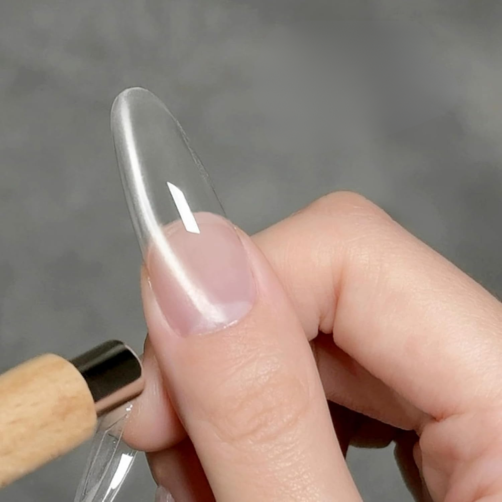 Halo Clear Cat Eye Gel swatch on a long clear nail showing a delicate silver magnetic line created with a cat-eye magnet.