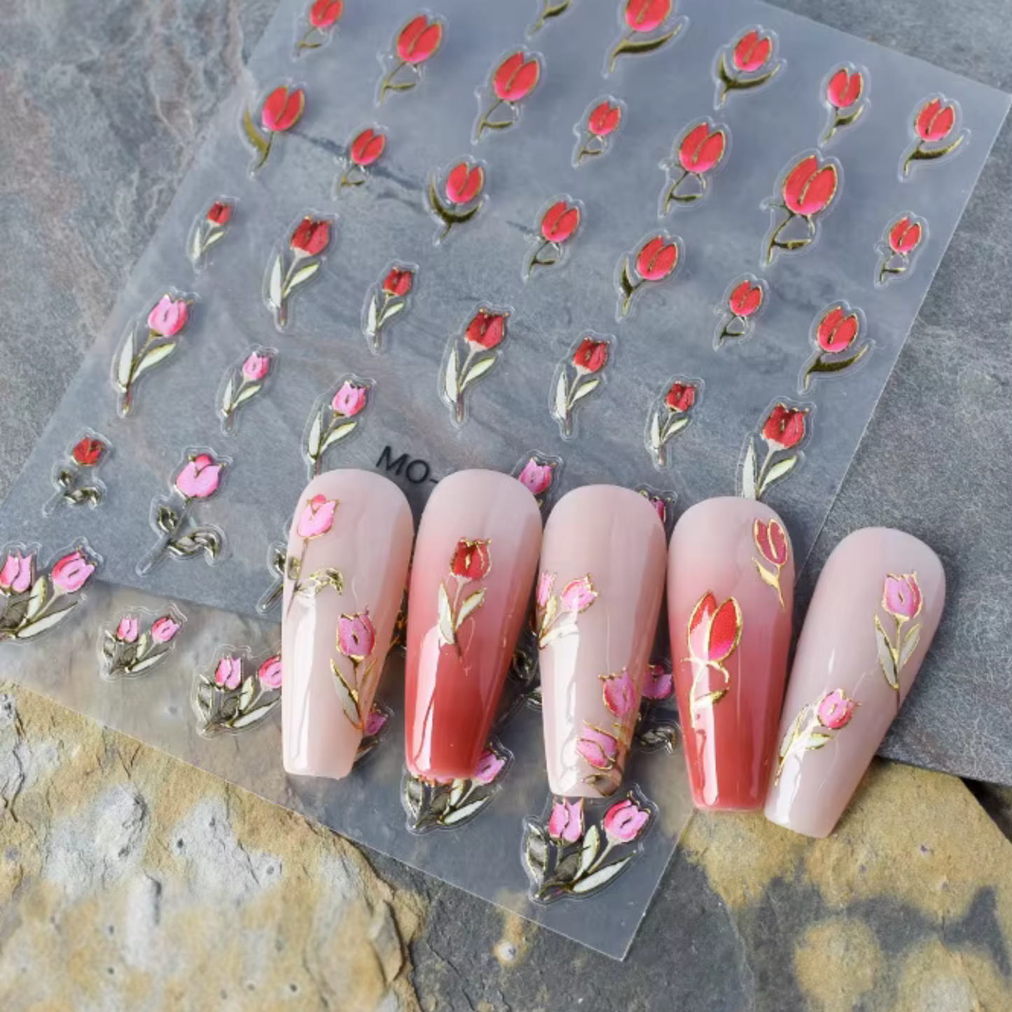 Nail art stickers with rose designs on a clear sheet, displayed on nails.