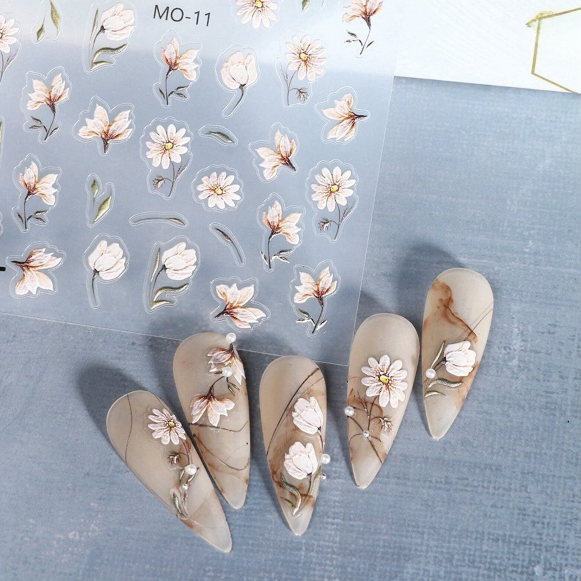 Nail art stickers with floral designs on a blue surface