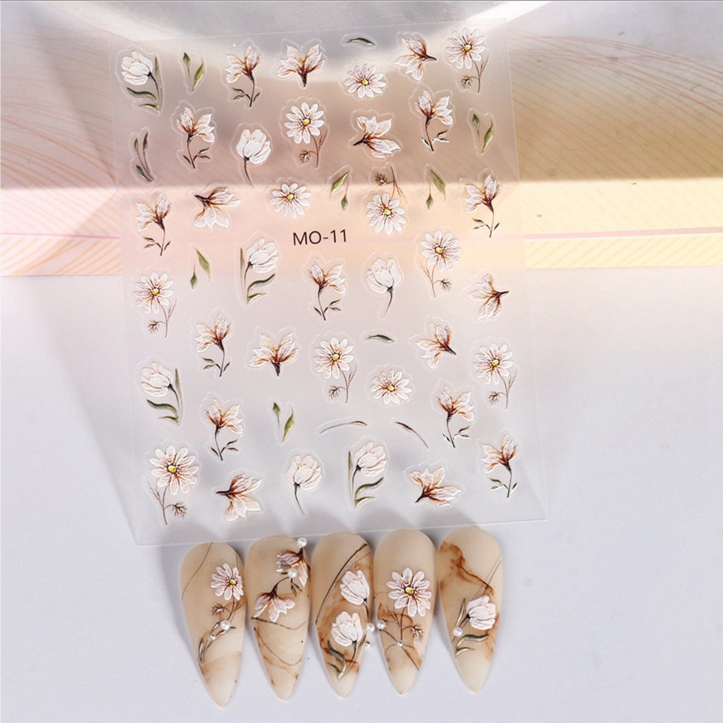 Floral nail decal sheet with matching nails on a light background