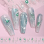 Decorative nails with green gemstones and silver accents on a pink background